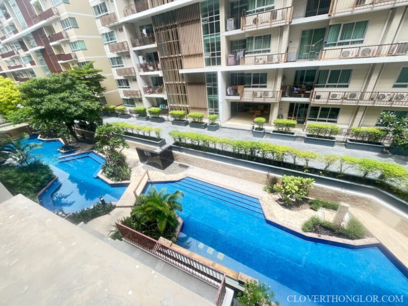 long pool High-angle view of The Clover Thonglor's winding resort-style pool and central courtyard, showcasing the lush landscaping and unit balconies.