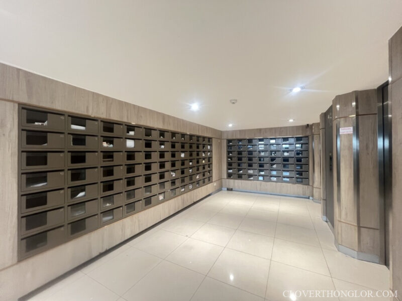 A clean, brightly lit mailroom at The Clover Thonglor Residence, featuring long banks of secure, modern, numbered mailboxes for residents.
